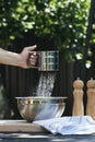 A woman`s hand sifting flour for baking