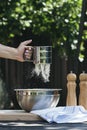 A woman`s hand sifting flour for baking