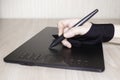 A woman`s hand in a special glove draws on a graphics tablet. Side view, tools for graphic drawing