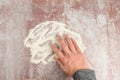 Womanâs hand spreading flour on a clear plastic mat on a pink marble countertop, preparation for baking