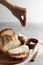 Woman`s hand sprinkling sugar artisan sliced toast bread with butter on wooden cutting board. Simple breakfast