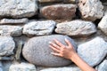 Woman`s hand on a stone wall. Texture of a stone wall. Part of a building wall. Close-up