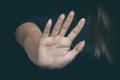 A woman`s hand with a stop gesture on a dark background. Copy space, selective focus