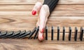 Woman`s hand stopping domino effect on the desk. Royalty Free Stock Photo