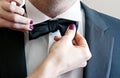 A woman`s hand straightens the groom`s bow tie