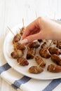 A woman's hand takes Bacon Wrapped Date, side view