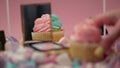 A woman`s hand takes a muffin with pink cream.