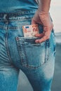 A woman`s hand takes out euro bills from the back pocket of her jeans. The concept of finance, savings, financial expenses. Close Royalty Free Stock Photo
