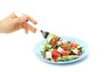 A woman`s hand takes a salad with a red orange with a fork, isolated on a white background