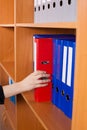Woman's hand taking a red folder from shelf Royalty Free Stock Photo