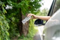 Woman's hand throwing away plastic bottle from car window on the road in green nature Royalty Free Stock Photo