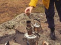 A woman& x27;s hand throws a cone into the chimney of a samovar. Drinking tea while traveling in nature