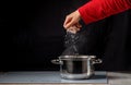 A woman's hand throws grains of rice into a pot of boiling water on the stove. Royalty Free Stock Photo