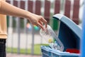 A woman's hand throws a plastic into the recycling container in a park. Ai generated