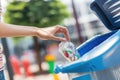 A woman's hand throws a plastic into the recycling container in a park. Ai generated