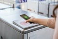 Woman`s hand ticking her transport ticket in the machine with her mobile phone on train station. NFC and contactless technology