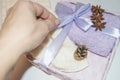 A woman`s hand ties a ribbon for a Christmas gift, packs Terry towels, decorates with cones, a bucket, the concept of Royalty Free Stock Photo