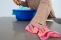 Woman`s hand using a colorful rag to wipe a kitchen counter top.blue bucket with cleaning rags In an unfocused background Royalty Free Stock Photo