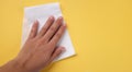 Woman`s hand wiping yellow desk with White tissue