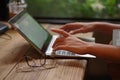 Woman`s hand working on keyboard laptop computer on wood table in a cafe Royalty Free Stock Photo