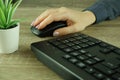 A woman's hand works with a mouse and keyboard manipulator. Caucasian Woman using a black wireless computer mouse on wooden Royalty Free Stock Photo