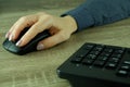 A woman's hand works with a mouse and keyboard manipulator. Caucasian Woman using a black wireless computer mouse on wooden Royalty Free Stock Photo