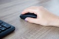 A woman's hand works with a mouse and keyboard manipulator. Caucasian Woman using a black wireless computer mouse on wooden Royalty Free Stock Photo