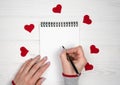 Woman`s hand writes writes congratulations to Valentine`s Day. Love romantic message. Flatlay composition. Royalty Free Stock Photo