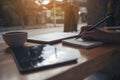 woman`s hand writing on a blank notebook with laptop , tablet and coffee cup on wooden table background Royalty Free Stock Photo