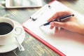 Woman`s hand writing on a blank planner at cafe