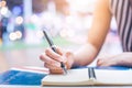 Woman`s hand writing on a notebook with a pen on a wooden desk. Royalty Free Stock Photo