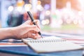 Woman`s hand writing on a notebook with a pen on a wooden desk. Royalty Free Stock Photo