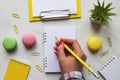 Woman's hand writing in notepad or sketchbook. Creative colorful artistic workplace. Table desk with notepads, pencil