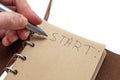A woman`s hand wrote with a pen in a notebook: Start. the concept of starting a new, achieving goals