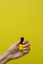 Woman's hand with yellow nails holding a bottle of yellow nail polish