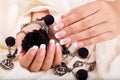 Hands with long artificial french manicured nails holding a necklace and black rose flower Royalty Free Stock Photo