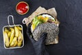 Woman`s hands in black rubber gloves are holding juicy black bun burger
