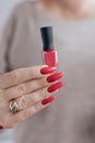 Woman`s hands and a bottle of red orange nail polish Royalty Free Stock Photo