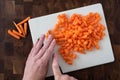 WomanÃ¢â¬â¢s hands chopping baby carrots, white cutting board on wood butcher block