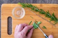 WomanÃ¢â¬â¢s hands chopping fresh sprig of rosemary with a paring knife on a bamboo cutting board, small glass bowl Royalty Free Stock Photo