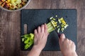 WomanÃ¢â¬â¢s hands chopping stalks of celery with chef knife on black cutting board Royalty Free Stock Photo