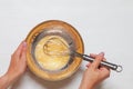 Woman`s hands close-up mixing eggs and sugar with wisk in a bowl