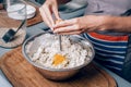 Woman`s hands crushing an egg and putting it into flour while making homemade pastry