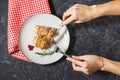 Woman`s hands cut the stuffed chicken breast wrapped in bacon on a plate on stone table Royalty Free Stock Photo