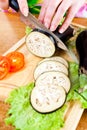 Woman's hands cutting aubergine eggplant