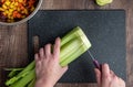 WomanÃ¢â¬â¢s hands cutting a bunch of celery, black cutting board and chef knife Royalty Free Stock Photo