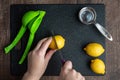 WomanÃ¢â¬â¢s hands cutting a lemon on a black cutting board, green citrus squeezer, measuring cup Royalty Free Stock Photo