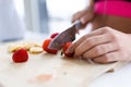 Woman`s hands while she cutting strawberries over wooden table in the kitchen Royalty Free Stock Photo