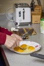 Woman\'s hands with a fork mixing eggs in a plate