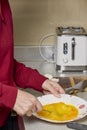 Woman's hands with a fork mixing eggs in a plate